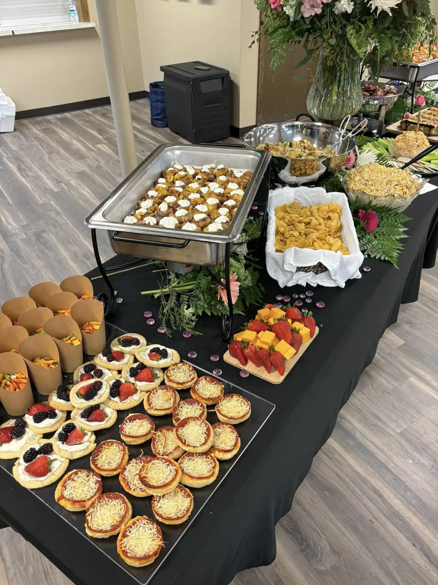 Event table with loaded potato skins, pasta salads, mini pizzas, and fruit cookies